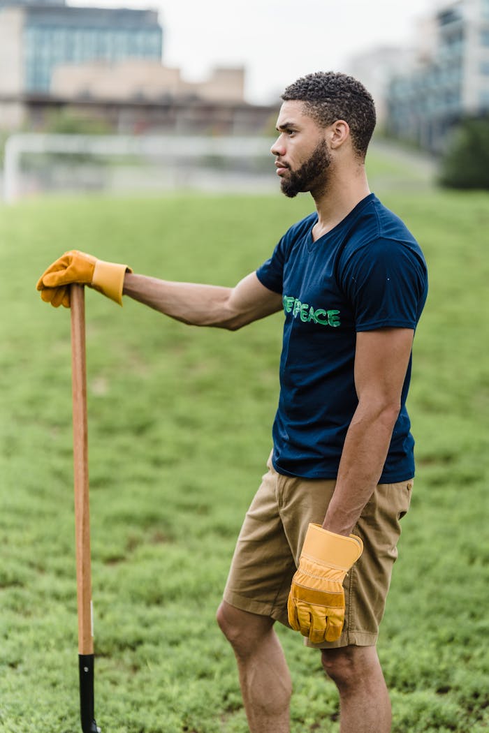 Man in Blue Crew Neck T-shirt and Brown Pants Holding Orange Stick